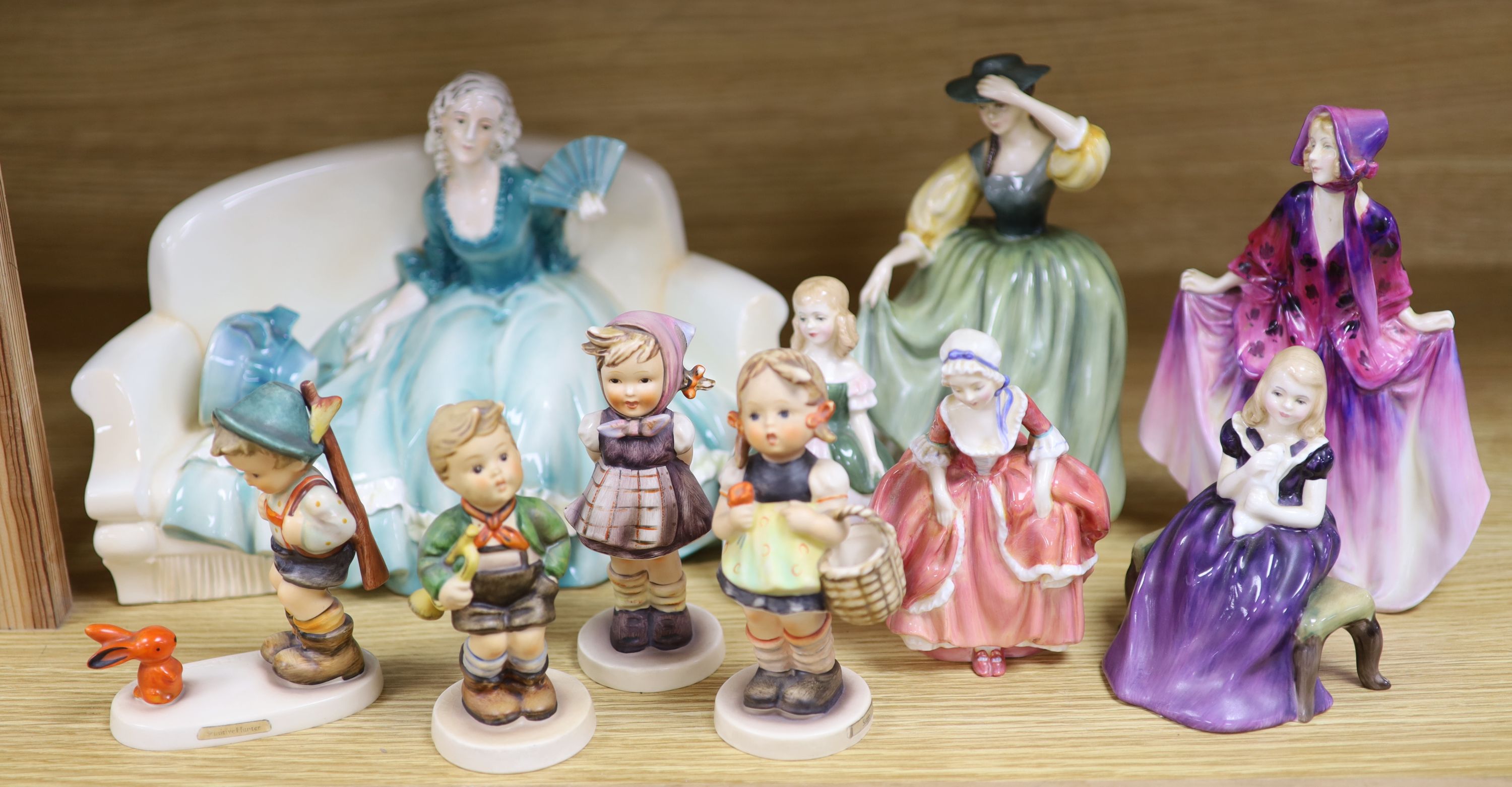 A collection of Hummel figures and Doulton ladies and a Katzhutte figure on a settee